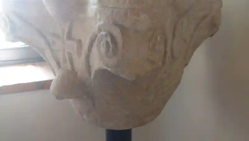Capital of pillar, cross on sphere, spiral shapes